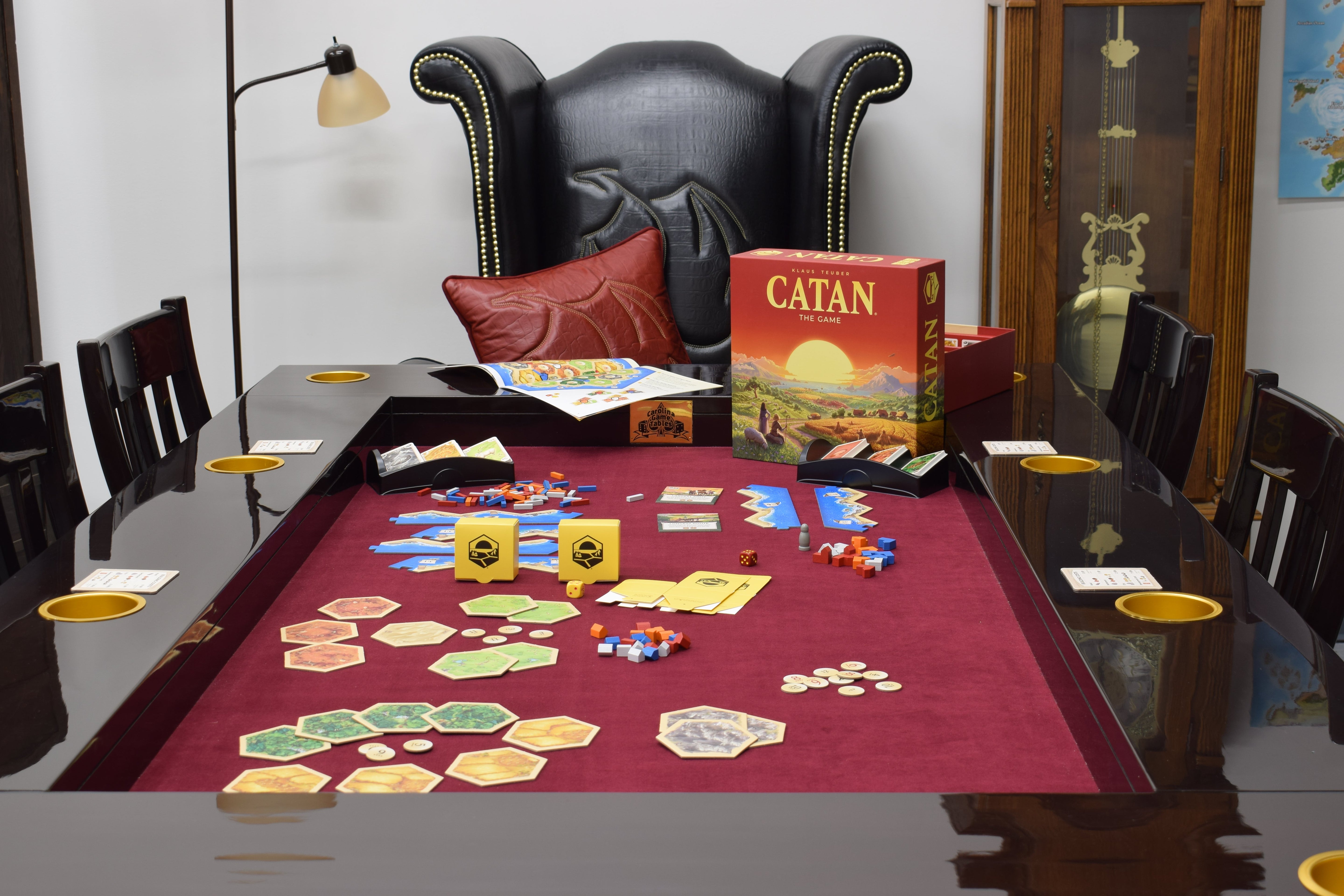 The all-new sixth edition of CATAN in English by CATAN Studios sits on a Dining Game Table from Carolina Game Tables. Behind the table sits the Deluxe Dragon Throne and Dragonhide Throw-pillow from the Elite Line by Carolina Game Tables.